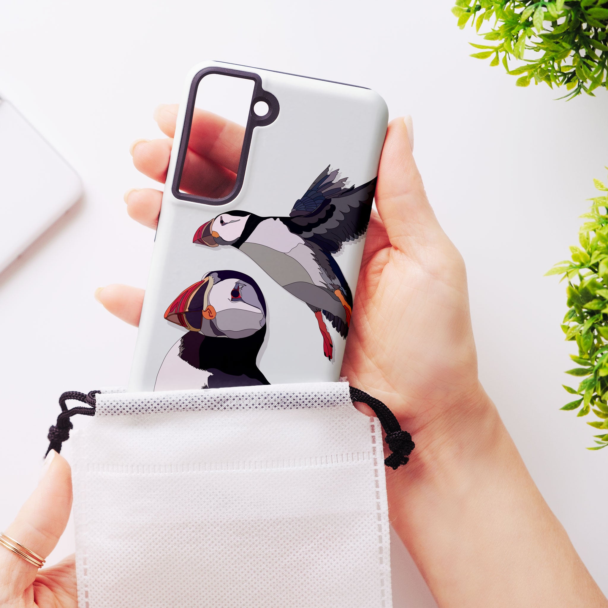 Close-up of a person holding a puffins tough phone case, highlighting its raised edges and camera cutout